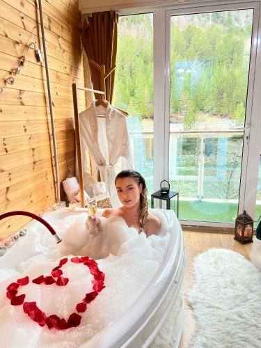 a woman is sitting in a bath tub at Guesthouse Marashi in Theth
