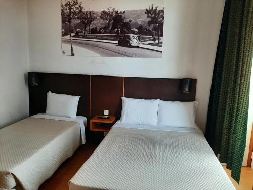a room with two beds and a picture on the wall at Residencial Aviz in Coimbra