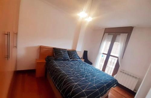 ein Schlafzimmer mit einem Bett mit blauer Decke und einem Fenster in der Unterkunft Chuchi house in Ramales de la Victoria