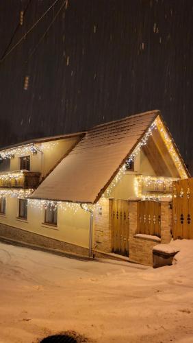 a house covered in christmas lights in the snow at Casa Hetrea in Sighişoara