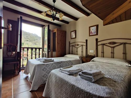 1 dormitorio con 2 camas y ventana grande en El Cantón en Cangas de Onís