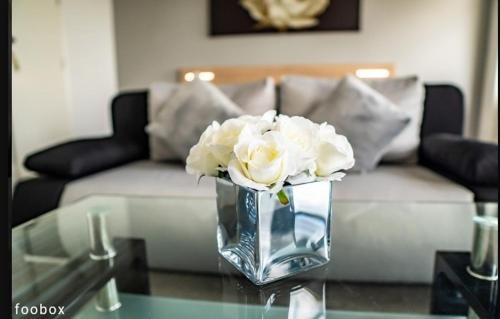 a vase with white roses sitting on a glass table at Weymouth Bay Hotel in Weymouth