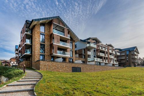 an apartment building on a hill with a grassy field at Apartament A121 Molo Lipno s infrasaunou - Residence Koubek in Lipno nad Vltavou