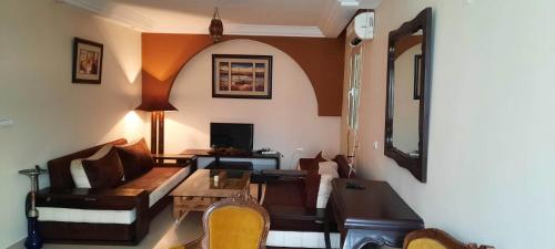 uma sala de estar com um sofá e uma mesa em Appartement Amilcar em Dar Salah Bey