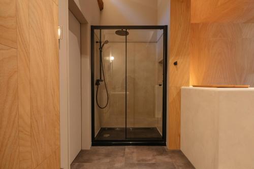 a shower with a glass door in a bathroom at APARTMENTS by Bed and Craft in Inami