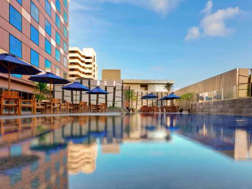 a swimming pool with blue umbrellas and tables and chairs at Grand Mercure Singapore Roxy in Singapore