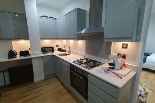 cocina con armarios blancos y fogones en cosy apartment Alexandra palace Haringey, London en Londres