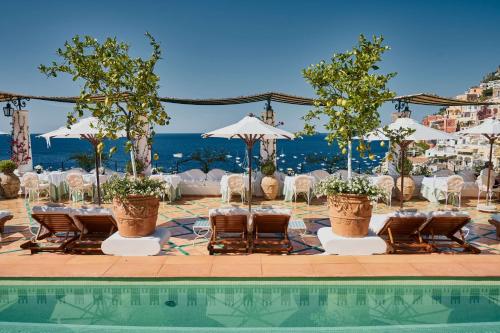 a pool with chairs and tables and umbrellas at Le Sirenuse in Positano