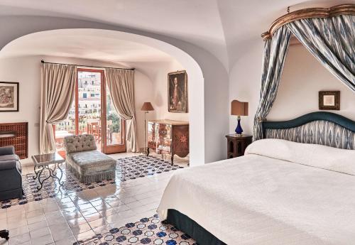 um quarto com uma cama king-size e uma lareira em Le Sirenuse em Positano