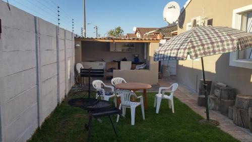 un patio con mesa, sillas y sombrilla en The Brookston Garden Cottage, en Ciudad del Cabo