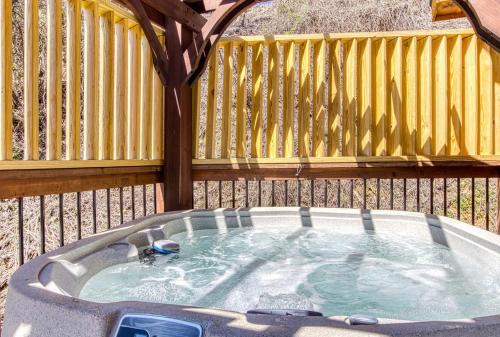 a hot tub in a backyard with a wooden fence at Ooglie Bear, Hot Tub, WIFI, Free Attraction Tickets!!! in Gatlinburg