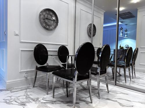 een eetkamer met zwarte stoelen en een klok aan de muur bij Hanza Tower Apartament Times Square in Szczecin
