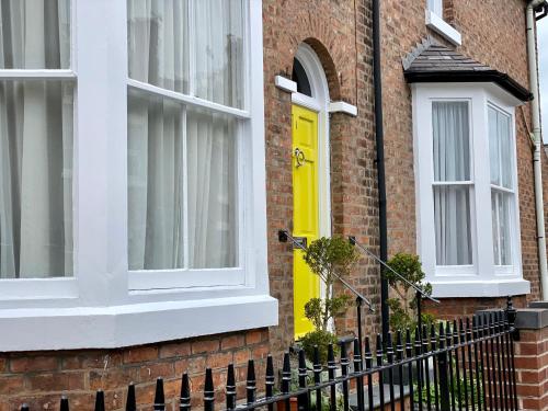 une porte jaune sur une maison en briques avec des fenêtres blanches dans l'établissement River walk . Shrewsbury.Shropshire.With parking., à Shrewsbury