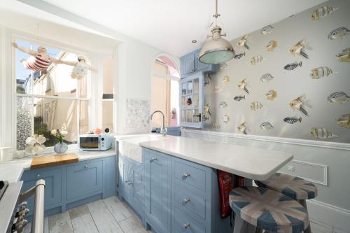 a kitchen with blue cabinets and a white counter top at Sea View Cottage Dream By The Water in Appledore