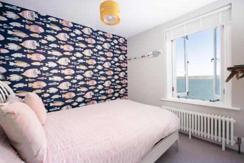 a bedroom with a bed with a floral wall at Sea View Cottage Dream By The Water in Appledore