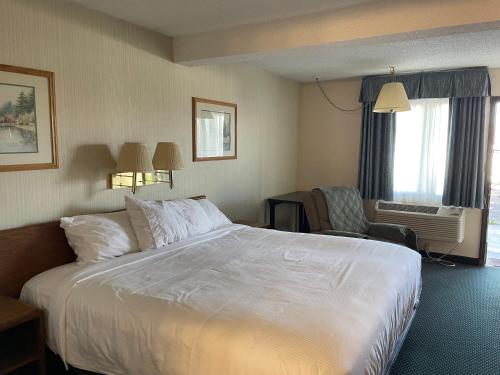una habitación de hotel con una cama grande y una silla en Landmark Inn, en Osawatomie