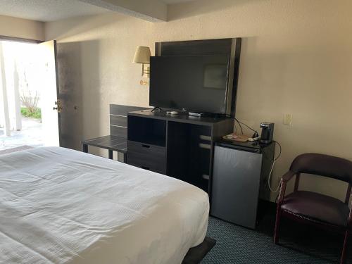 a hotel room with a bed and a flat screen tv at Landmark Inn in Osawatomie