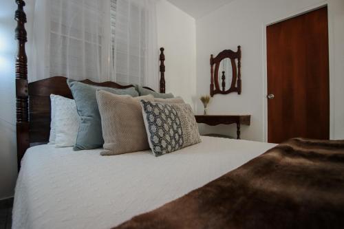 a bedroom with a bed with pillows and a mirror at Hacienda Tres Casitas in Cabo Rojo