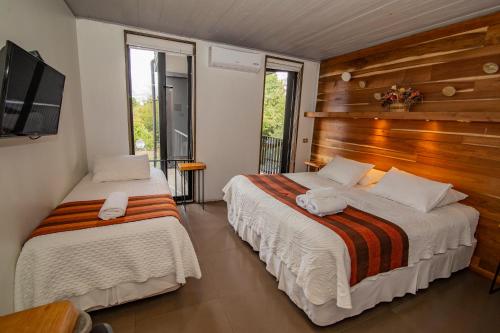 a bedroom with two beds and a flat screen tv at Hotel Cumbres del Sur in Pucón