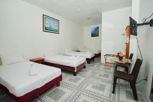 Habitación con 3 camas, mesa y silla en Hostal Gardner en Puerto Ayora