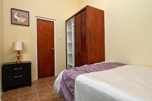 a bedroom with a bed and a wooden cabinet at La Vue 2 in Anse La Raye