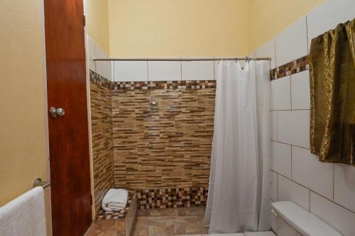 a bathroom with a shower with a white shower curtain at La Vue 2 in Anse La Raye