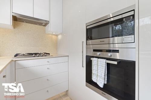 a kitchen with a stove and a microwave at Mowamba E5 in Thredbo