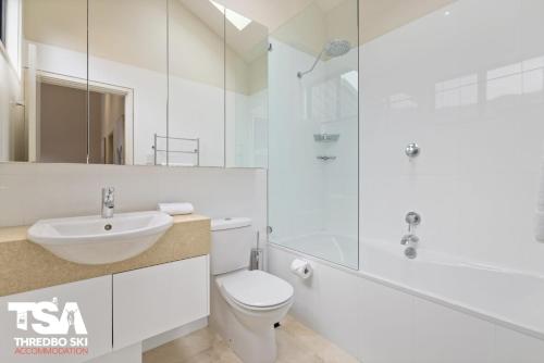a white bathroom with a toilet and a sink at Mowamba E5 in Thredbo