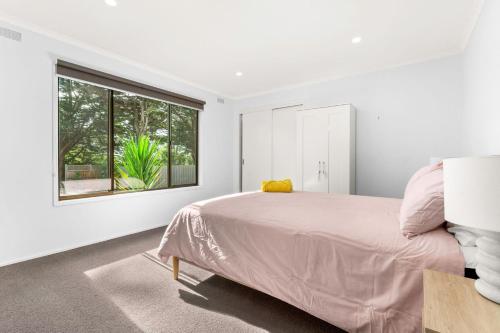 a white bedroom with a bed and a window at Rhyll Rendezvous in Rhyll
