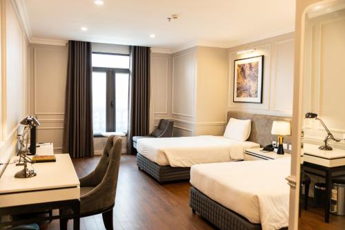 a hotel room with two beds and a desk at Thiên Ân Hotel Bắc Giang in Bắc Giang