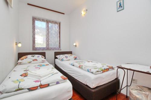 Pokój z 2 łóżkami, stołem i oknem w obiekcie Apartments with parking spaces Baska, Krk - 18861 w Bašce