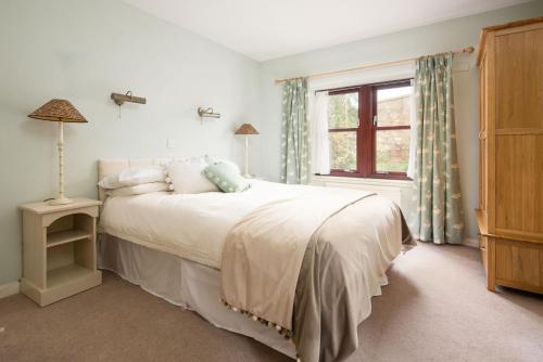 a bedroom with a white bed and a window at Westwood Cottage in Longniddry