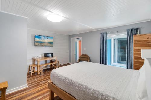 a bedroom with a bed and a desk and a window at Anchor Inn Motel in Oak Island