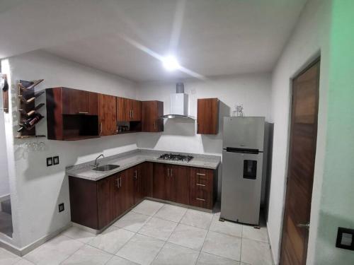 La cuisine est équipée d'armoires en bois et d'un réfrigérateur en acier inoxydable. dans l'établissement Villa el roble, à Acapulco