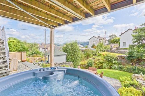 a hot tub on a patio with a view of a yard at Netherbeck Cottage Coniston in Coniston