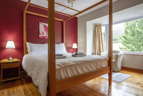 a bedroom with a four poster bed with red walls at Netherbeck Cottage Coniston in Coniston