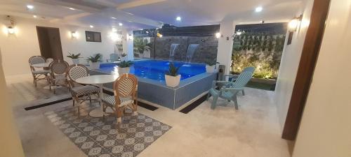 a large swimming pool in a room with chairs and a table at Aurora Suites in Manila