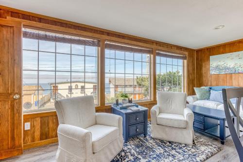 a bedroom with two chairs and a bed and windows at A Slice Above in Lincoln City