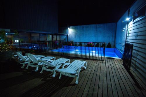 a row of white chairs sitting on a deck at night at Hotel Cumbres del Sur in Pucón