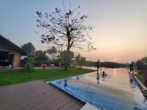 a group of people standing around a swimming pool at La Y Riverview in Hue