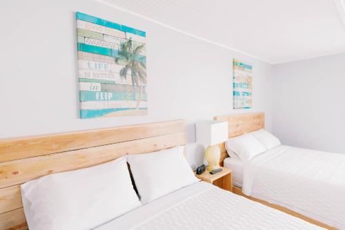 two beds in a room with white walls at Anchor Inn Motel in Oak Island