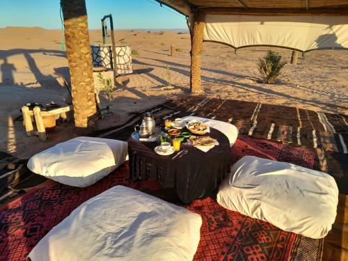 a table with food and drinks on it in the desert at Bivouac La Dune Blanche in Mhamid