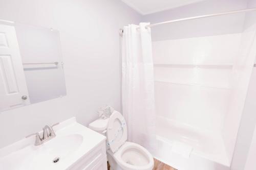 uma casa de banho branca com um WC e um chuveiro em Anchor Inn Motel em Oak Island