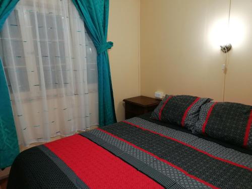 a bedroom with a bed with a red and black blanket at Cabaña "Descanso playero" in Quintero