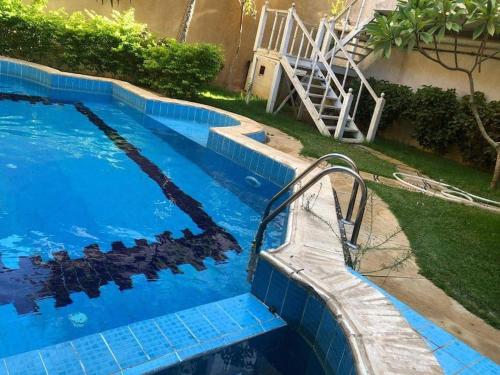 a swimming pool with a bench next to a house at فيلا مبهجة مع مسبح وحديقة رائعة in 6th Of October