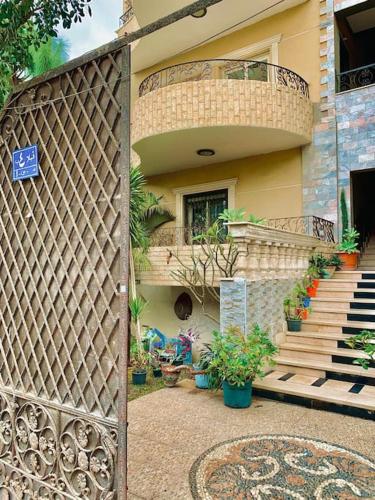 a gate to a house with a staircase and potted plants at فيلا مبهجة مع مسبح وحديقة رائعة in 6th Of October