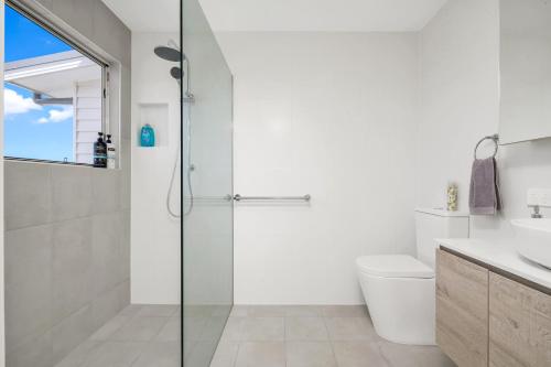 a bathroom with a shower and a toilet and a sink at Newly Built Spacious Beach Home in The Entrance