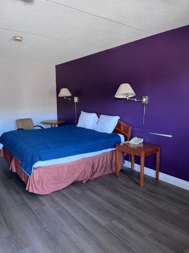 a bedroom with a large bed with a purple wall at Knights Inn - Park Villa Motel, Midland in Midland