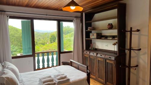 - une chambre avec un lit et une grande fenêtre dans l'établissement Pousada na Cervejaria Altezza, à Venda Nova do Imigrante