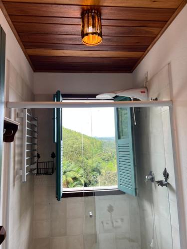 uma casa de banho com um chuveiro, uma janela e uma cabina de duche em vidro. em Pousada na Cervejaria Altezza em Venda Nova do Imigrante